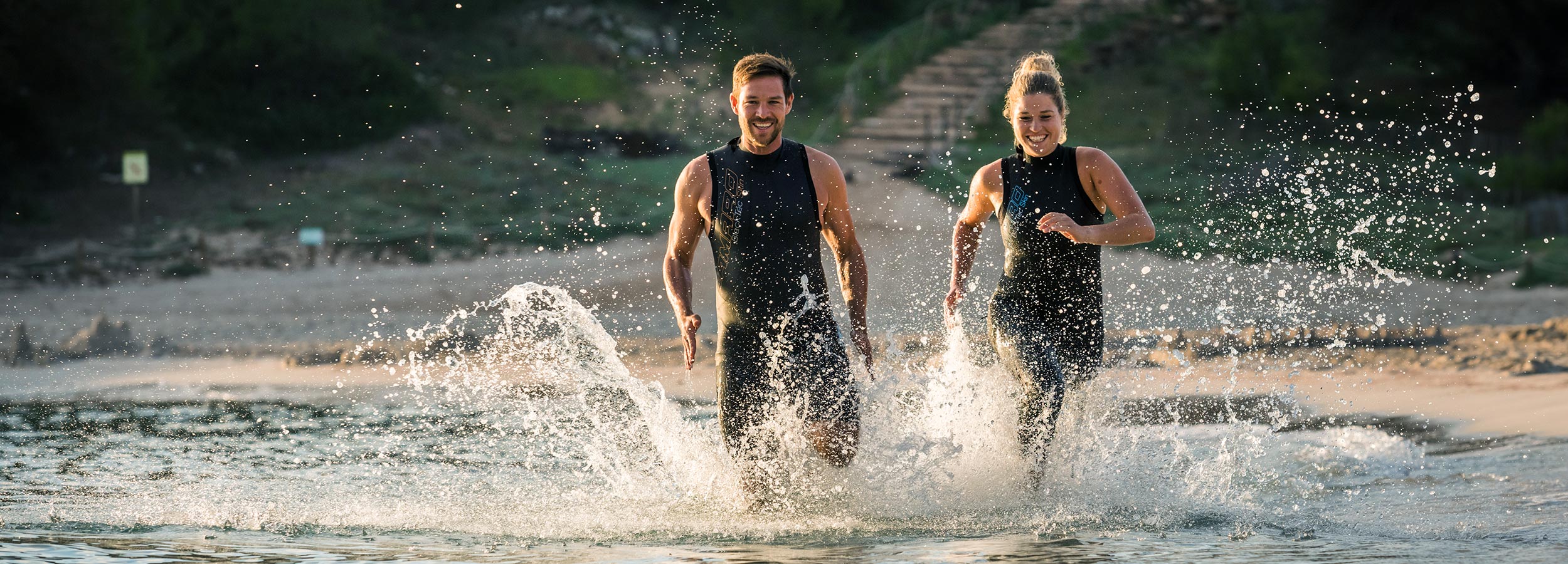 Triathlon Swim mit Camaro Mann und Frau laufen im Wasser und tragen Anzüge von Camaro